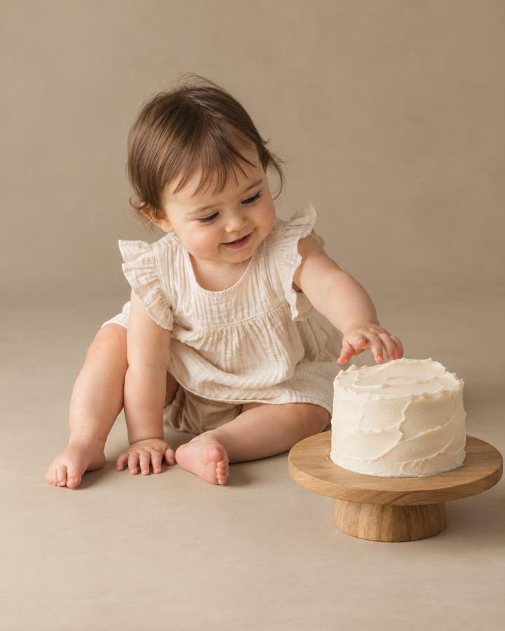 Cake Smash: reaching towards cake on oak stand